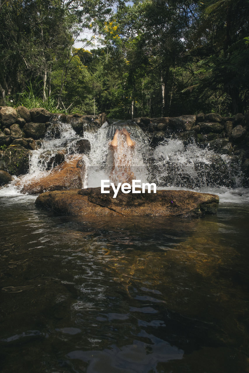 Woman bathing in waterfall at forest