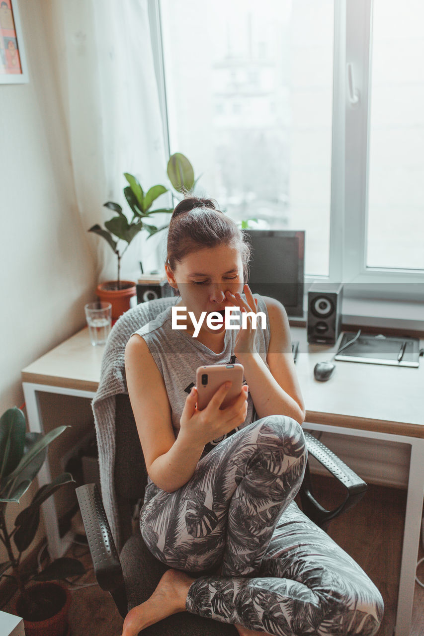 High angle view of woman using smart phone while sitting at home