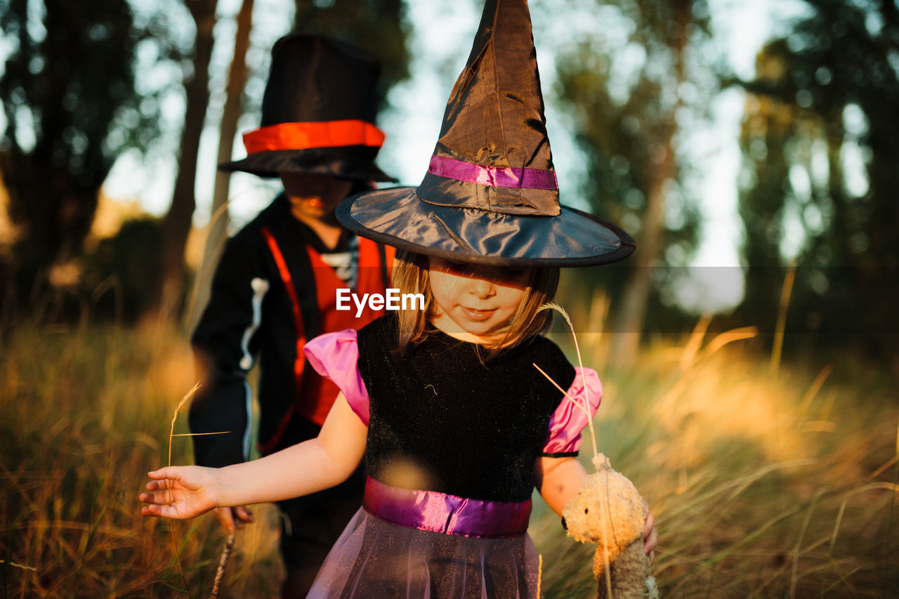 Girl with brother wearing costume during halloween at forest