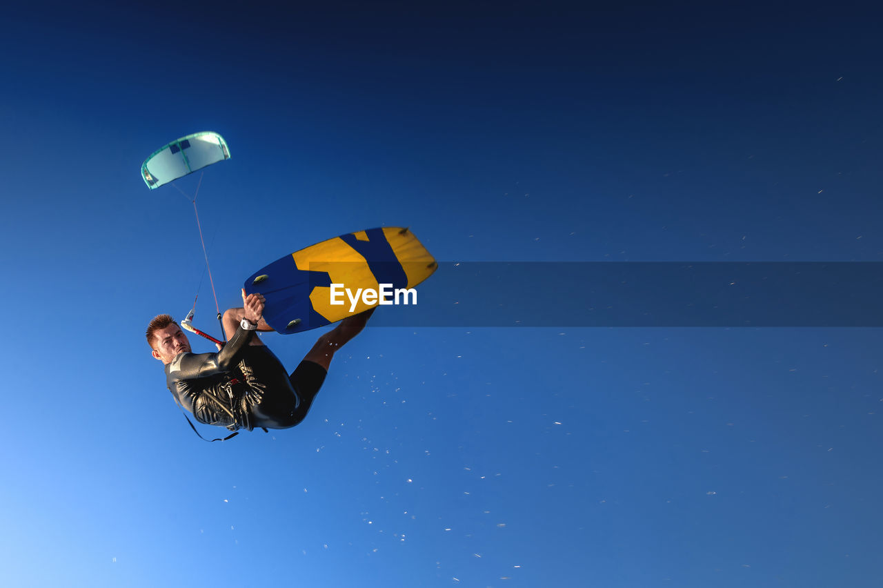 A kitesurfer rides while suspended in the air. kitesurfer jumps against a beautiful blue sky