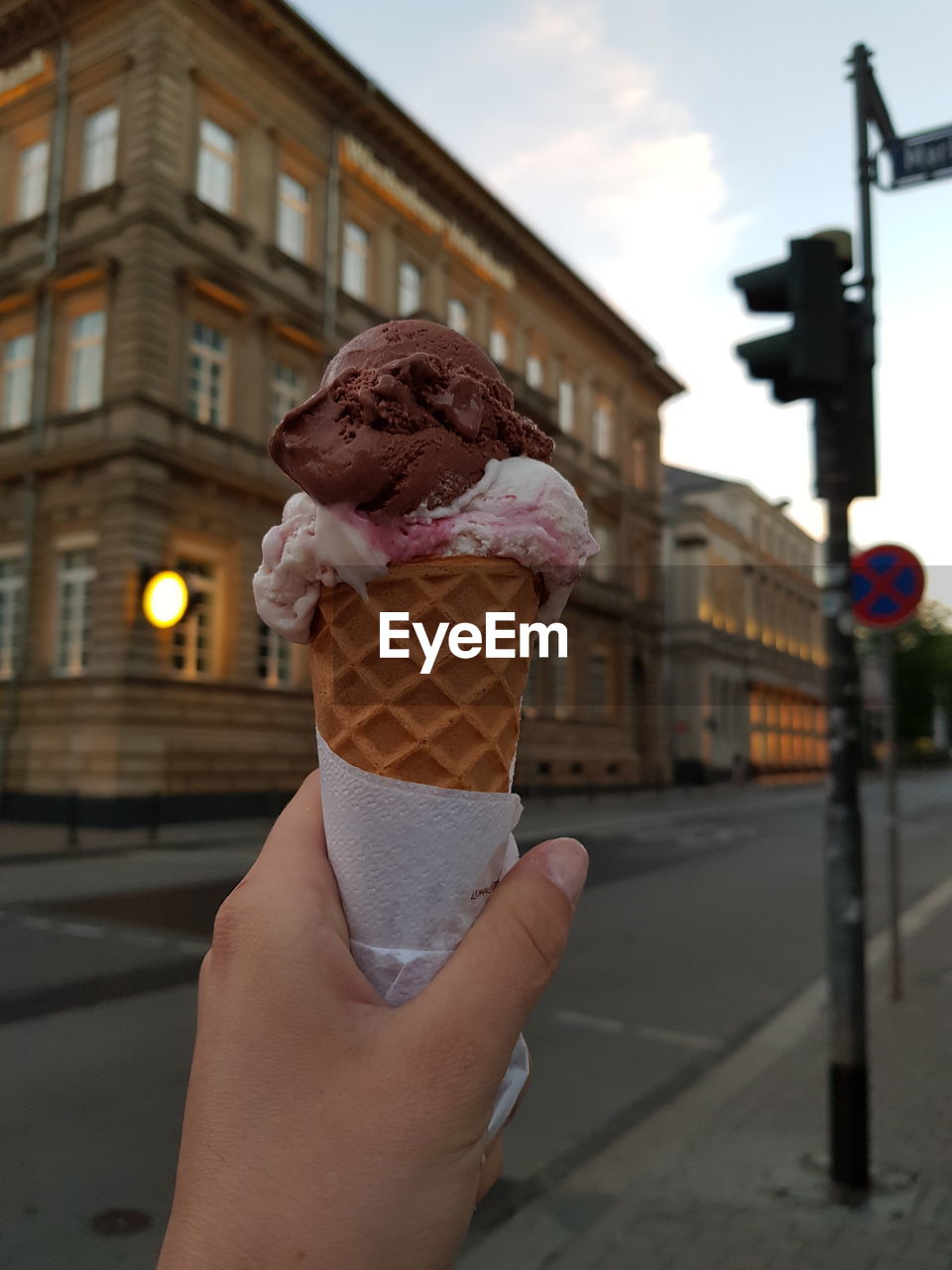 MIDSECTION OF PERSON HOLDING ICE CREAM CONE IN CITY DURING WINTER