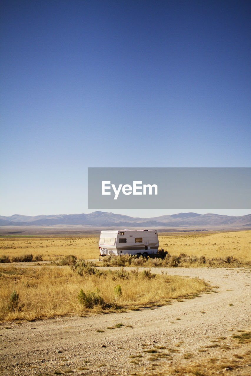 Camper van parked on field against clear sky