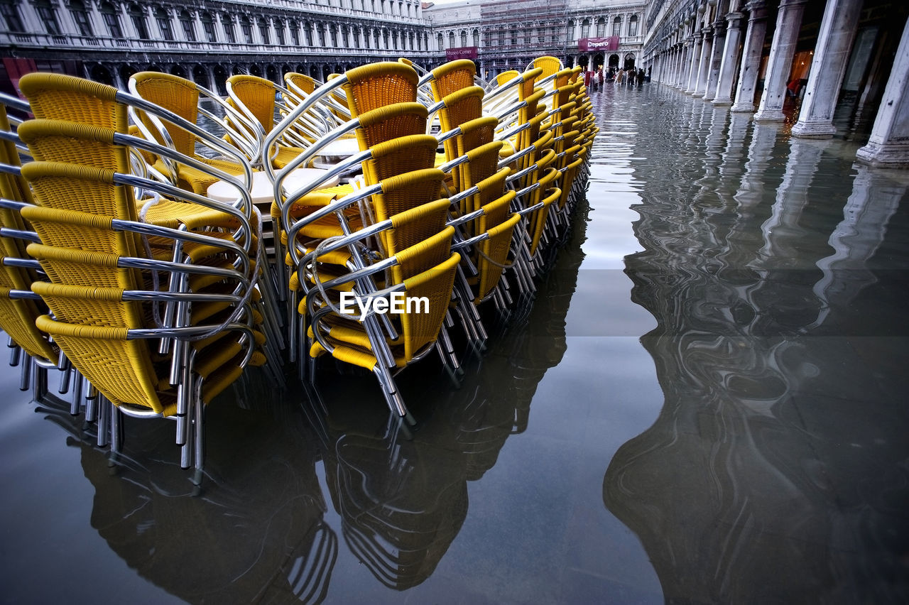 Yellow stacked chairs on water filled walkway during flood at piazza san marco