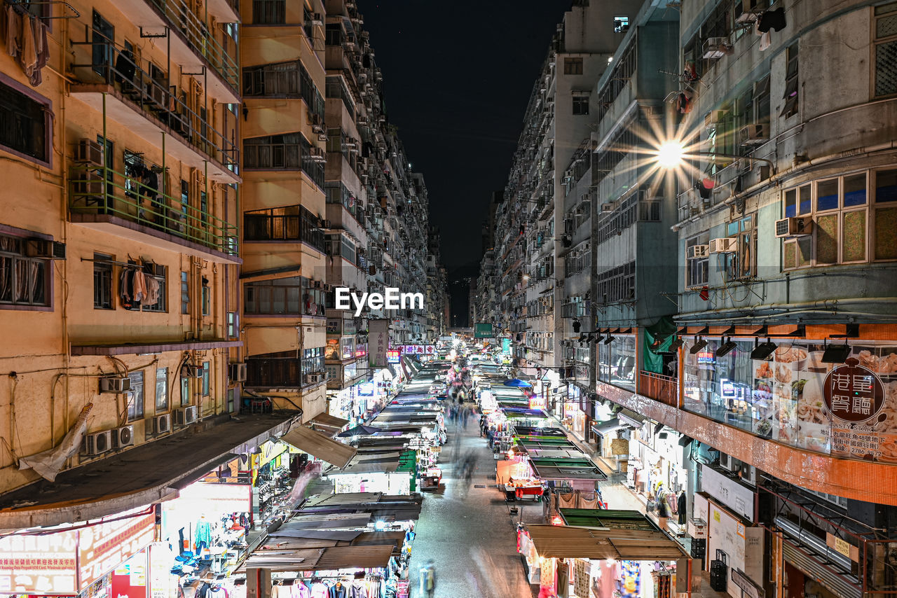 CITY STREET AMIDST BUILDINGS AT NIGHT