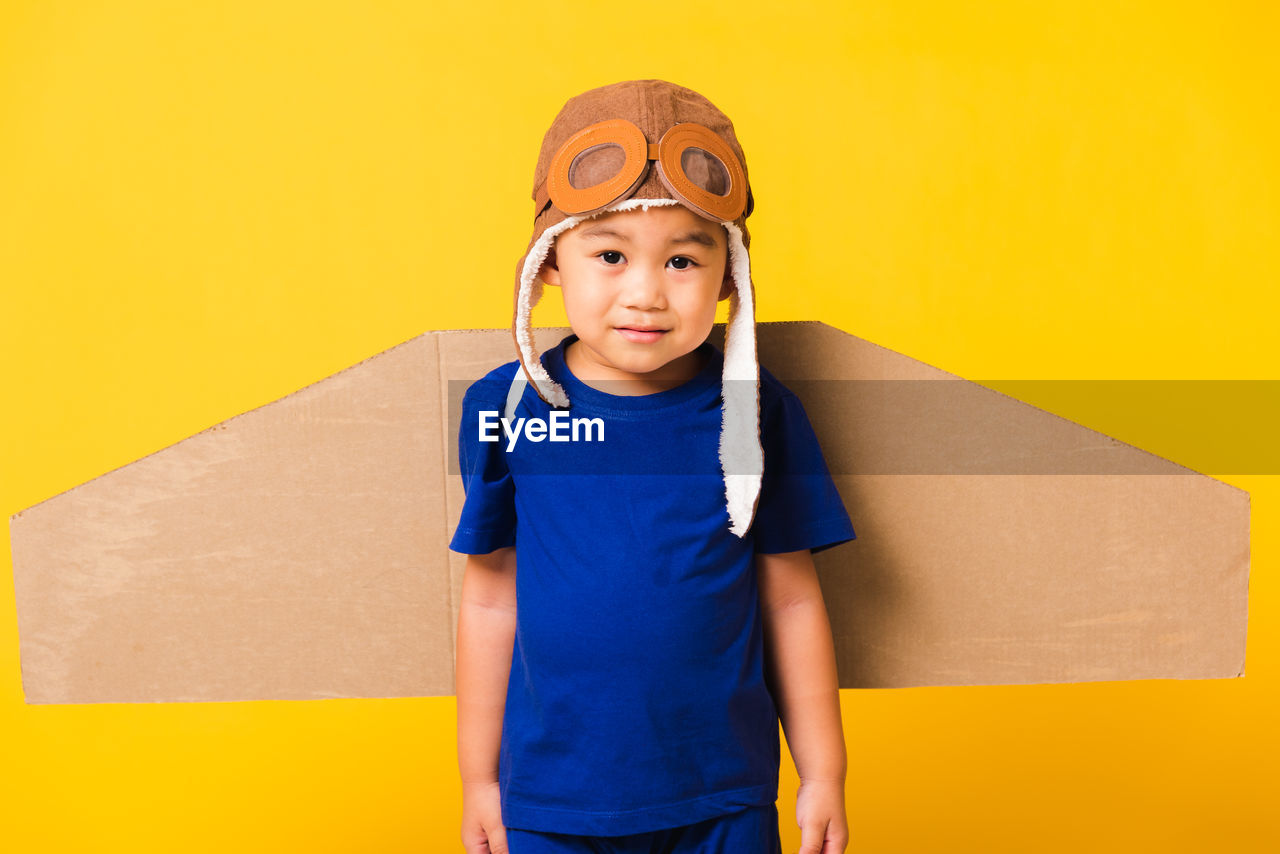 Portrait of boy wearing costume standing against yellow background