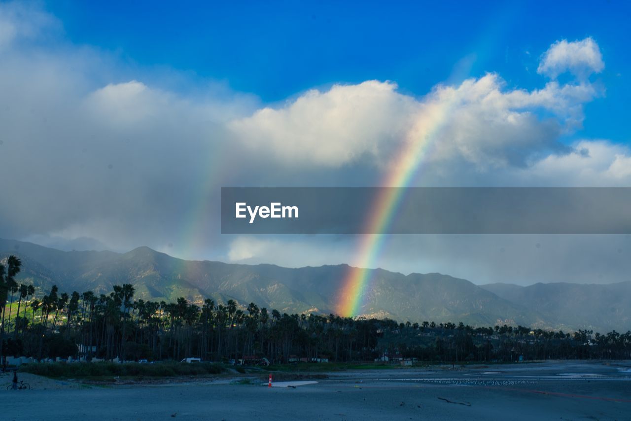 rainbow, sky, cloud, beauty in nature, mountain, scenics - nature, environment, nature, multi colored, landscape, water, land, tree, tranquility, no people, tranquil scene, mountain range, idyllic, plant, double rainbow, travel destinations, outdoors, spectrum, dusk, natural phenomenon, day, sunlight, travel, wet, sea, non-urban scene, storm, blue, rain, horizon, beach