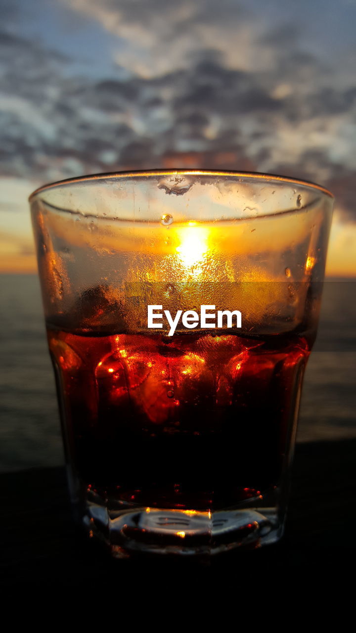 Close-up of drink in glass against sunset