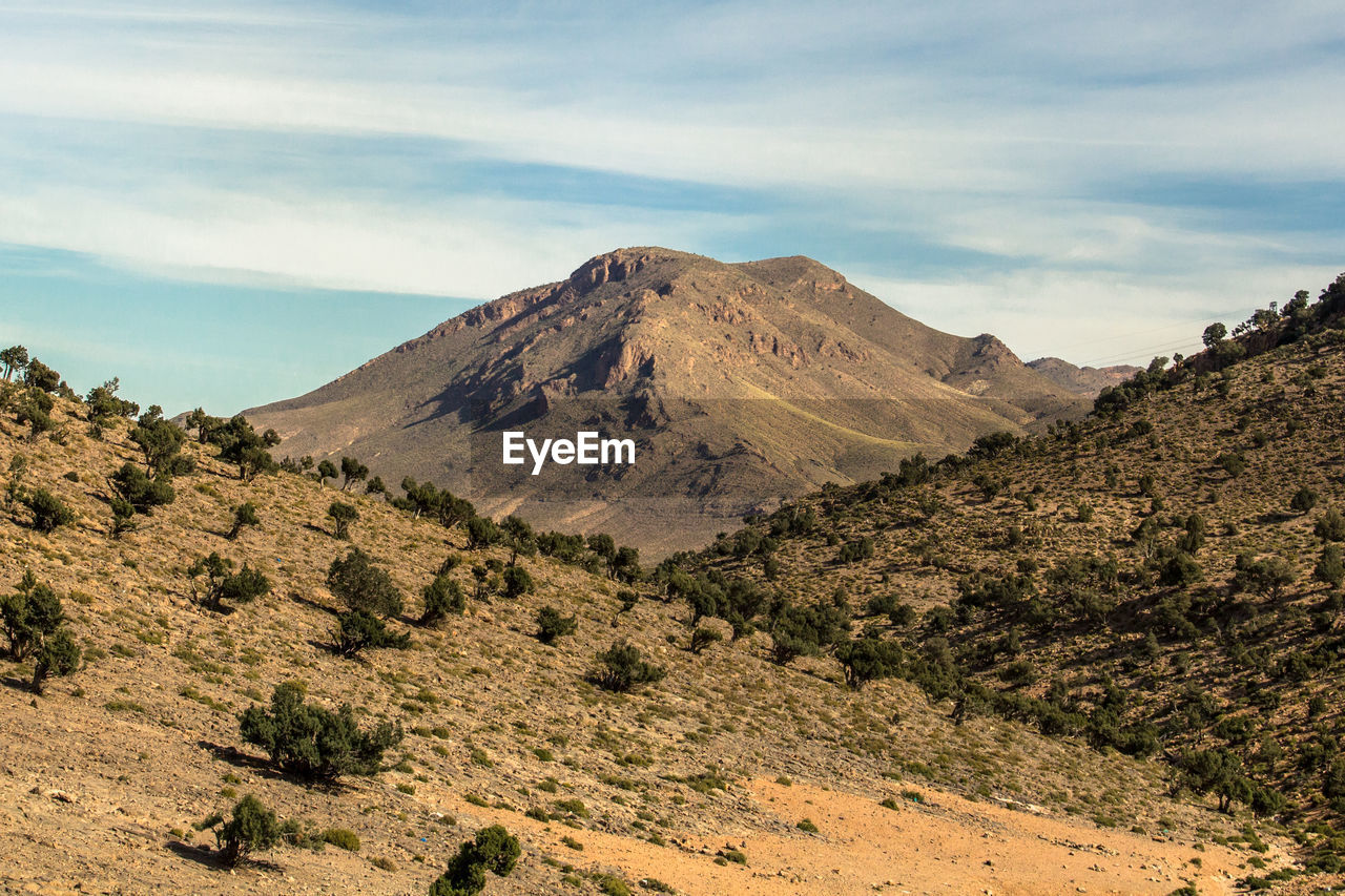 Scenic view of dry atlas mountains against a cloudy sky, ifrane, morocco