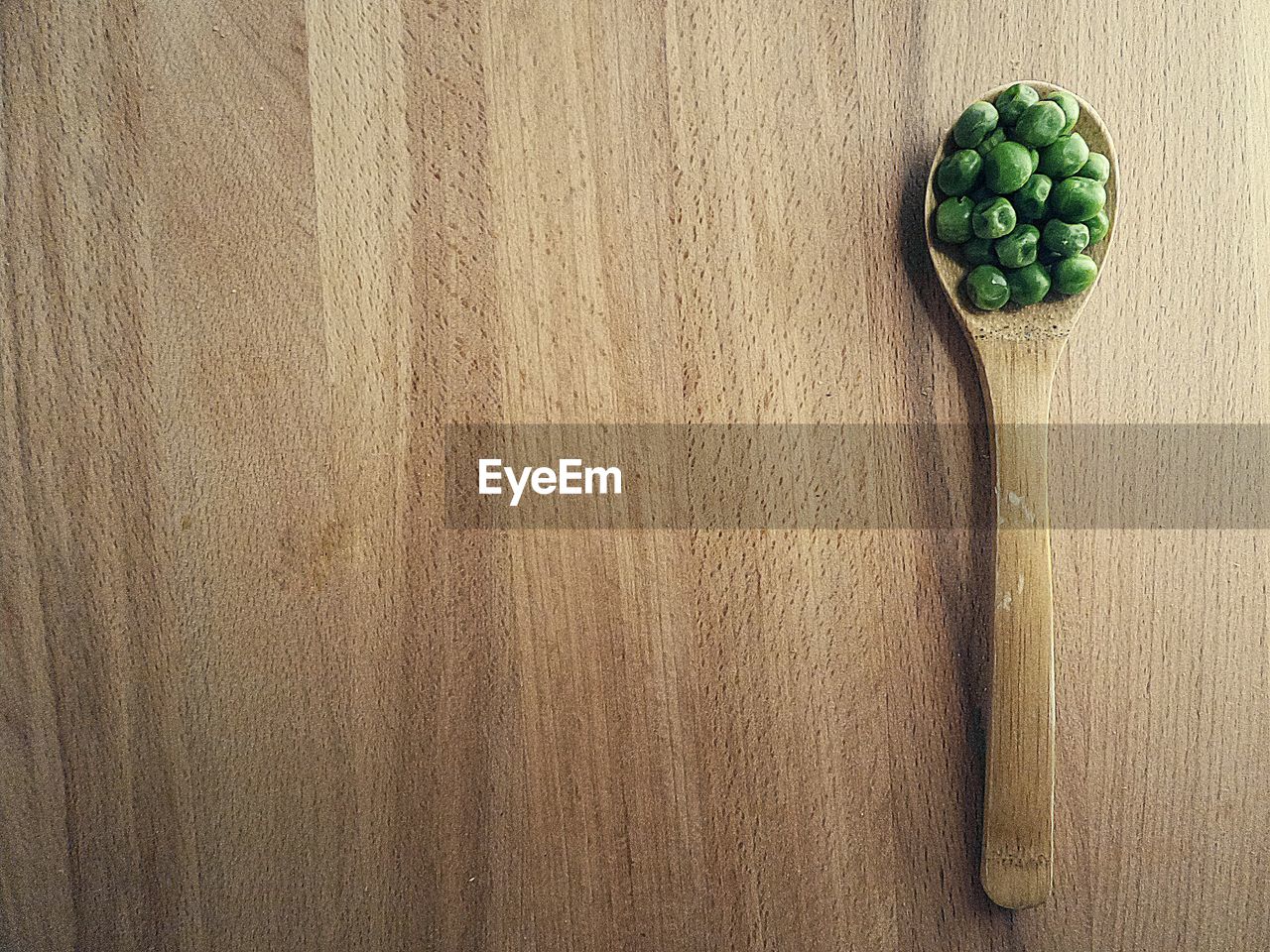 Directly above view of green peas in wooden spoon on table