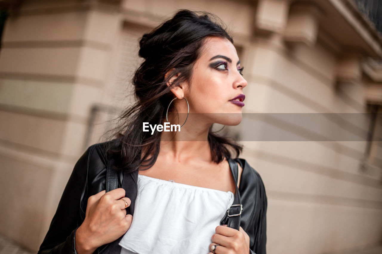 A young woman looking away walking in the city looking away