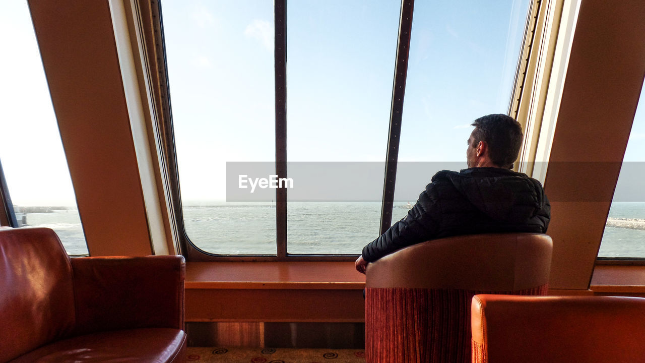 Rear view of man sitting on chair in boat 