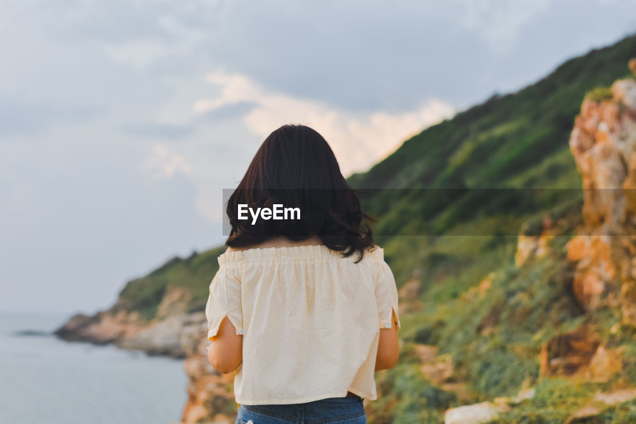 Rear view of woman looking at mountains against sky