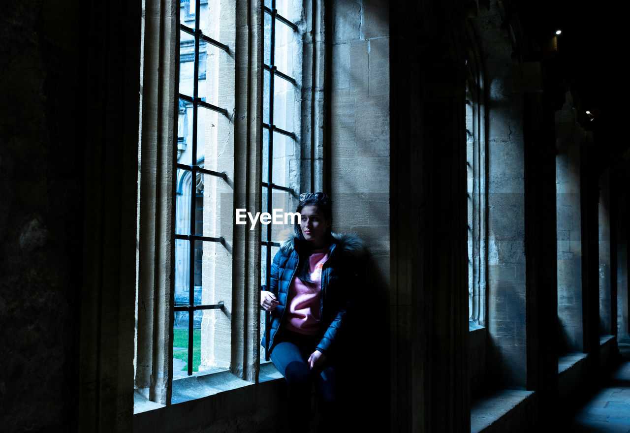 Woman wearing warm clothing while looking through window