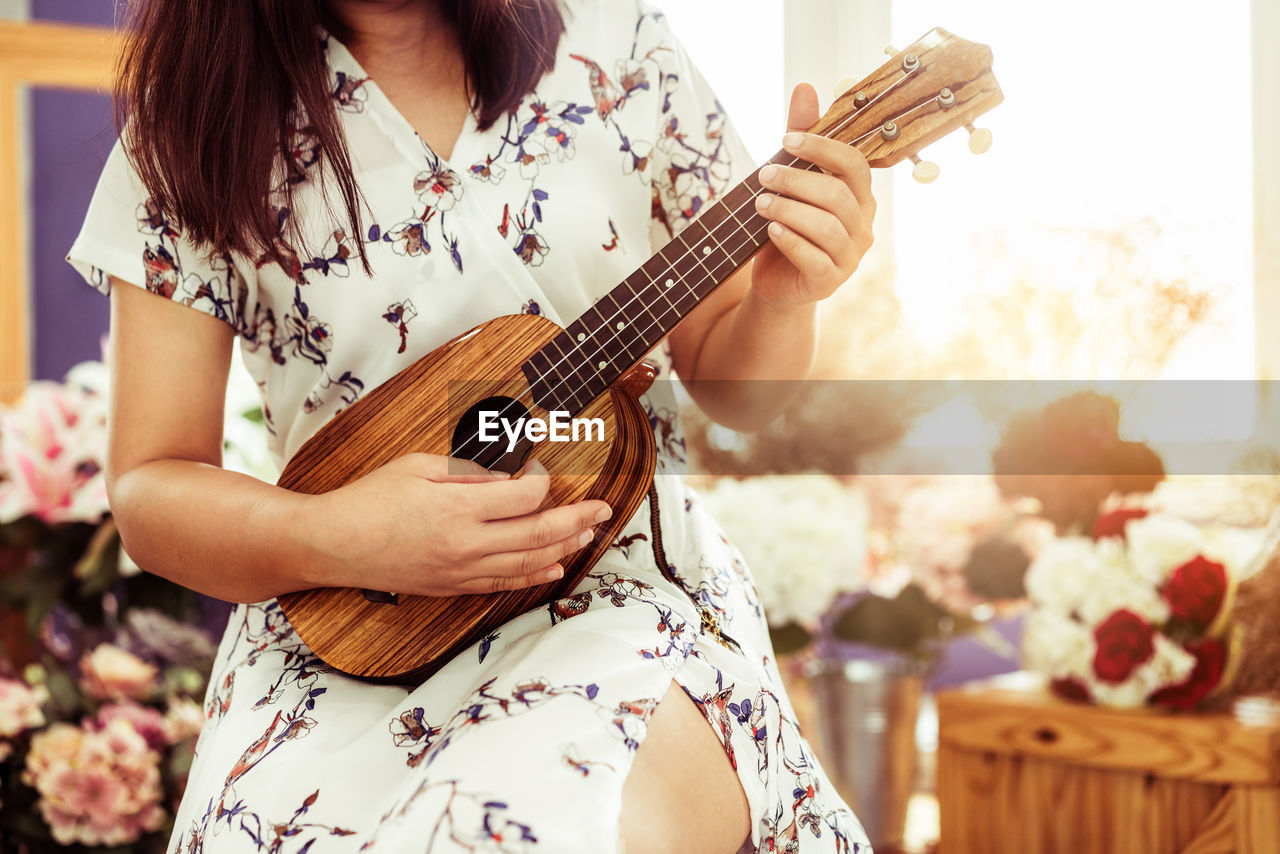 Midsection of woman playing ukulele