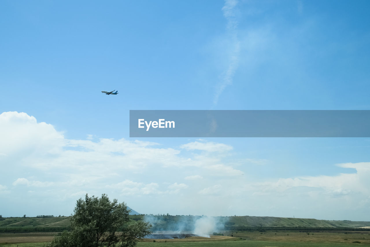 LOW ANGLE VIEW OF AIRPLANE FLYING OVER CLOUDS