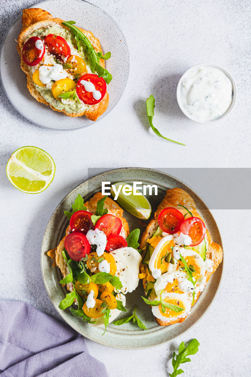 Variety of croissant sandwiches with tomato, cucumber, mozzarella, eggs and avocado.