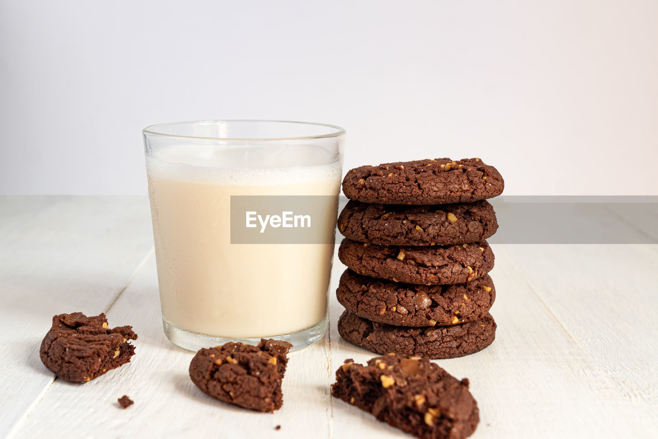 Stuck of chocolate brownie cookies and glass of coconut milk on wooden background. homemade pastry.