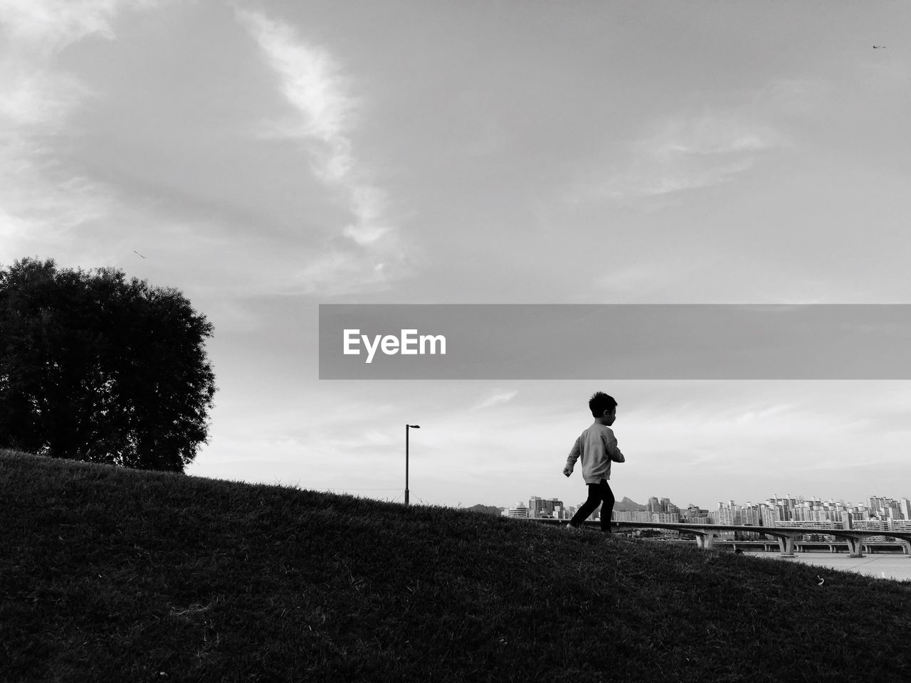 Boy walking on field against sky