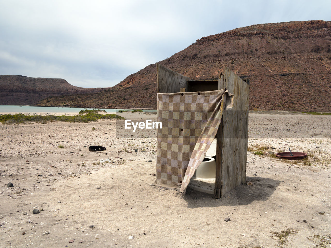 Outhouse by mountain at desert against sky