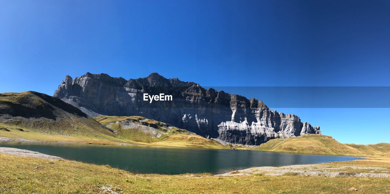 Scenic view of lake and mountains against clear blue sky