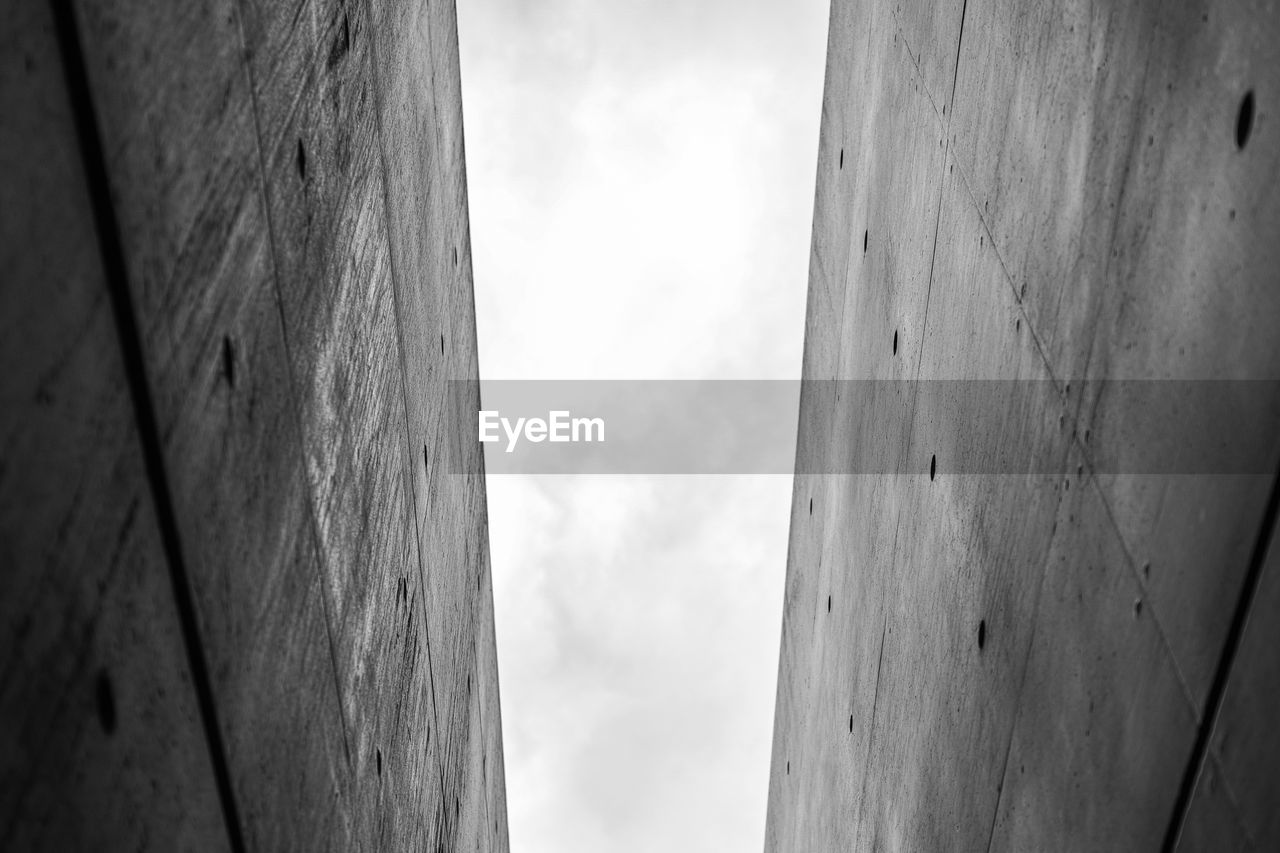 LOW ANGLE VIEW OF WALL AGAINST CLOUDY SKY