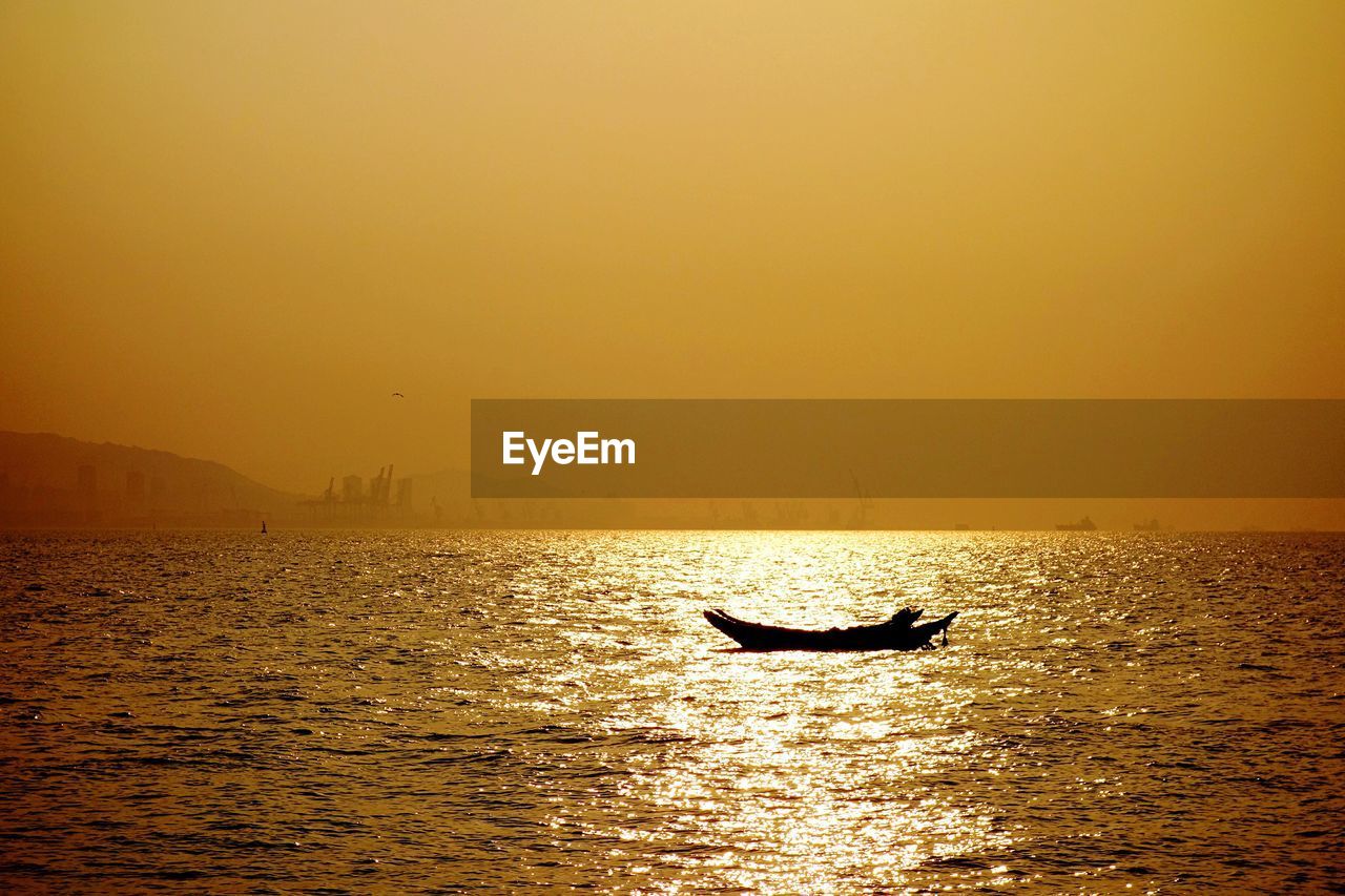 Silhouette boat in sea against sky during sunset