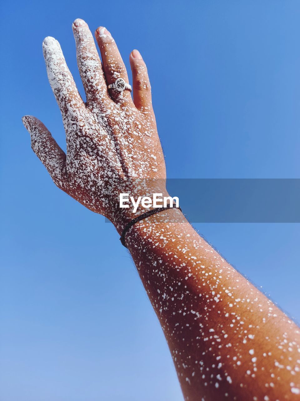 Close-up of painted hand against clear blue sky