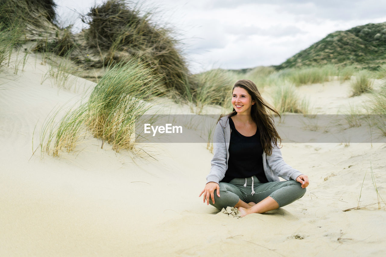 Smiling young woman sitting at beach