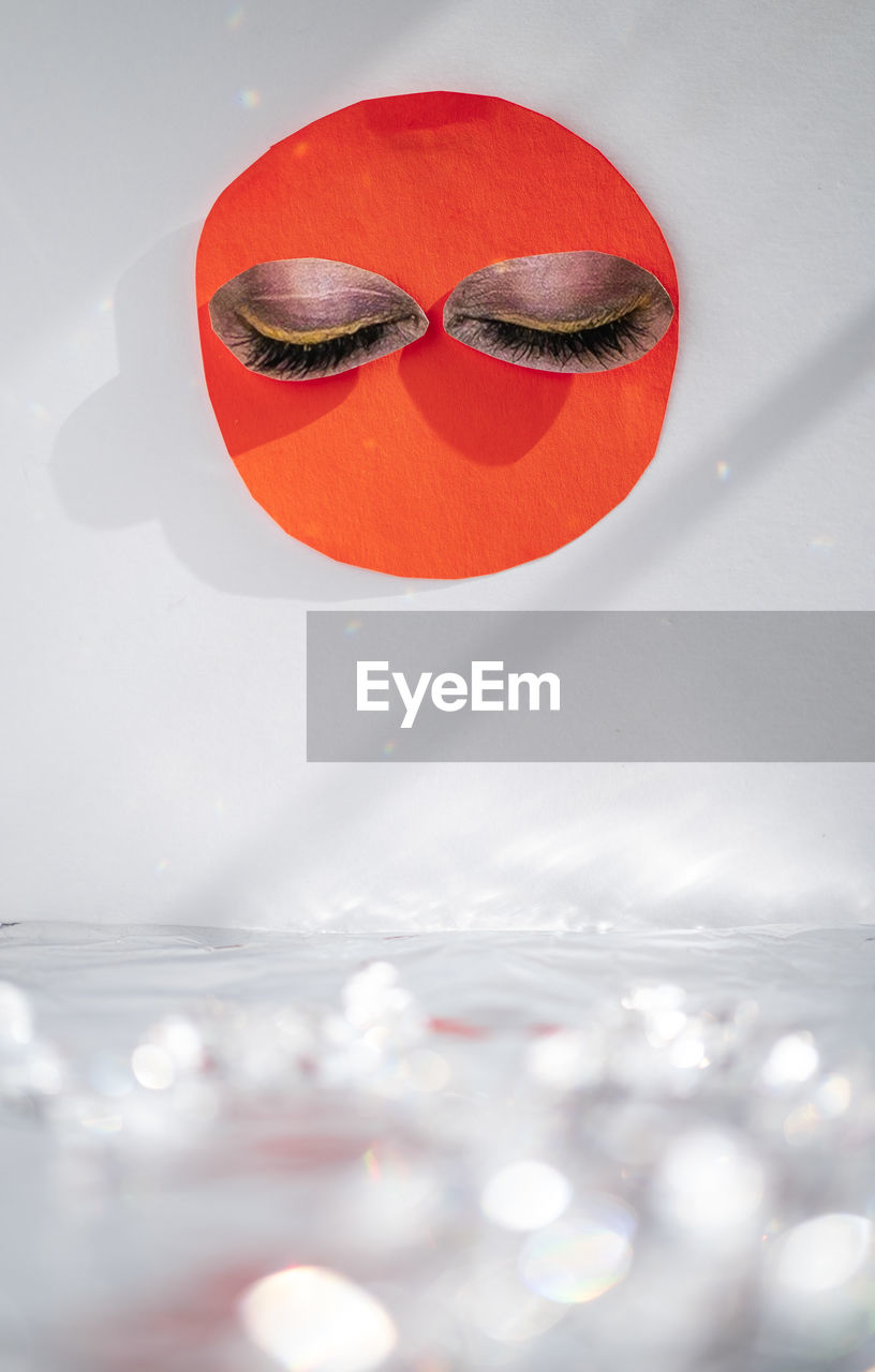 A cut-out of sun shape with eyes, above sparkling surface