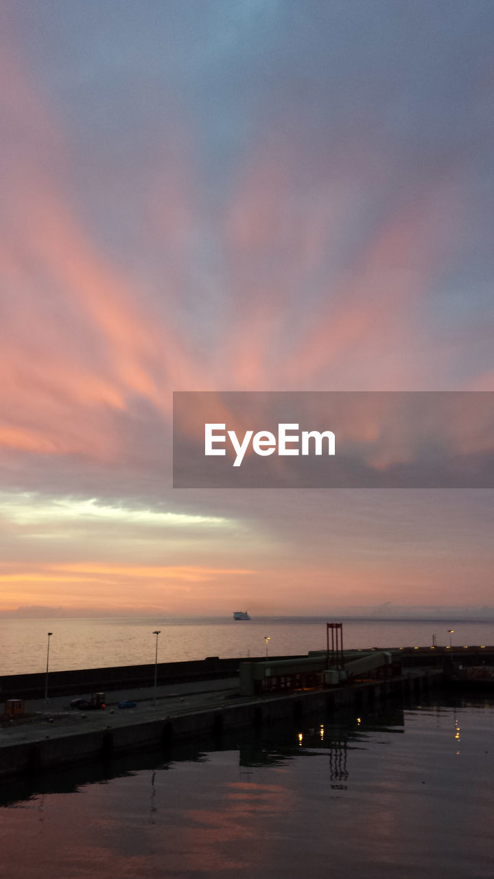 Concrete pier by calm sea at dawn