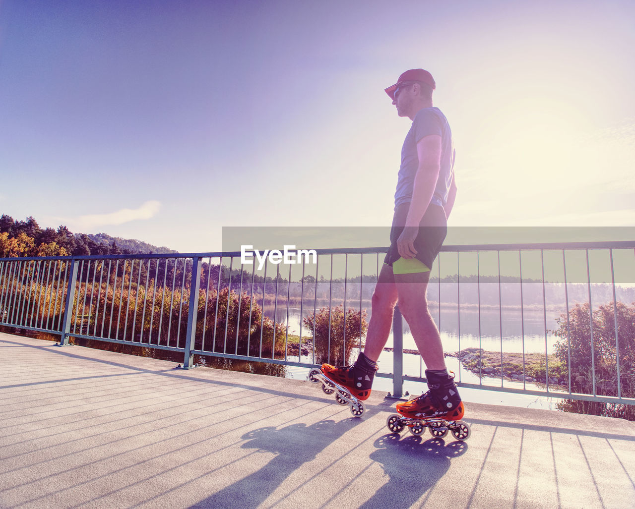 Inline skater ride on lake bridge. boy legs in in-line hard shell boots blades.