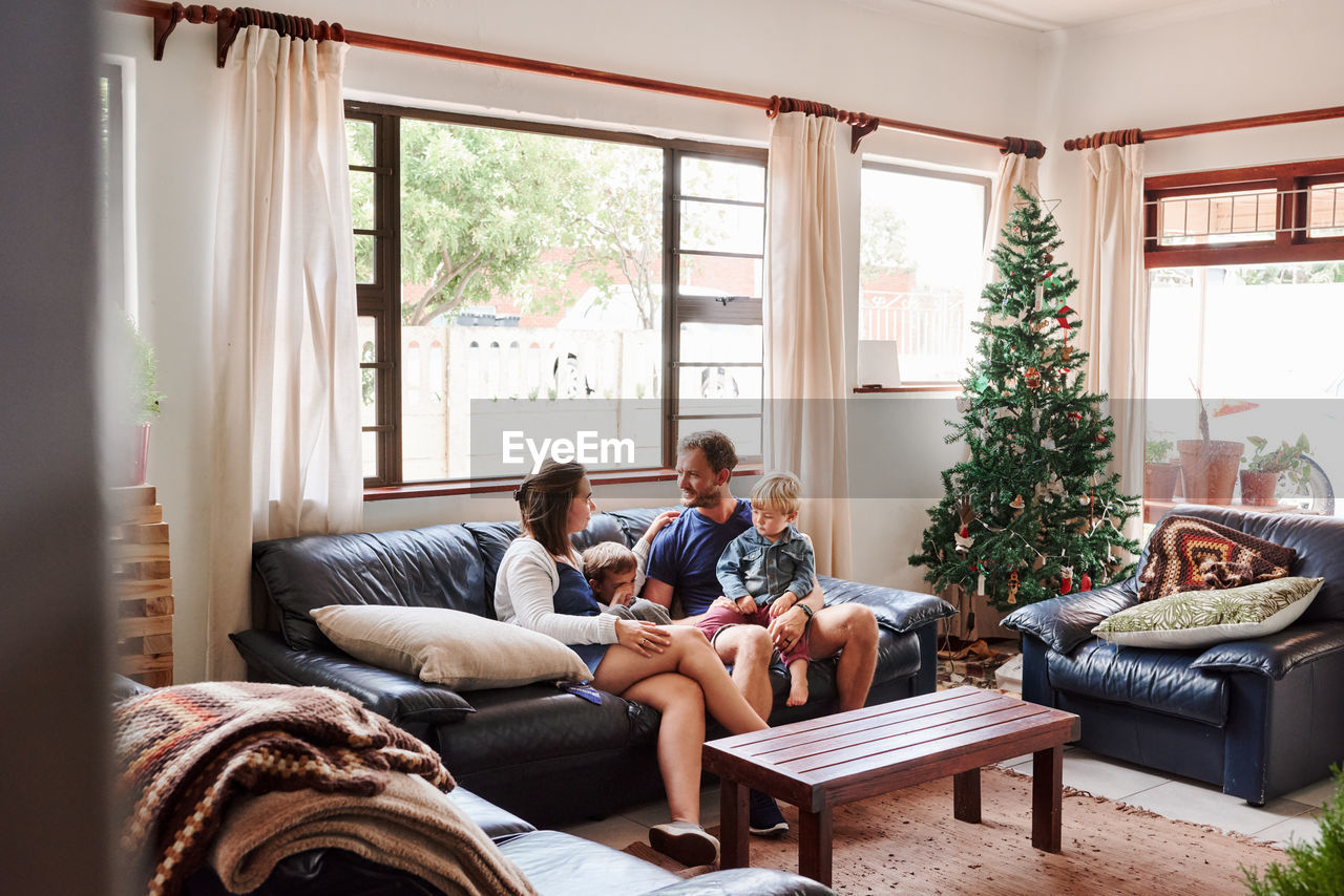Parents and kids sitting on sofa at home