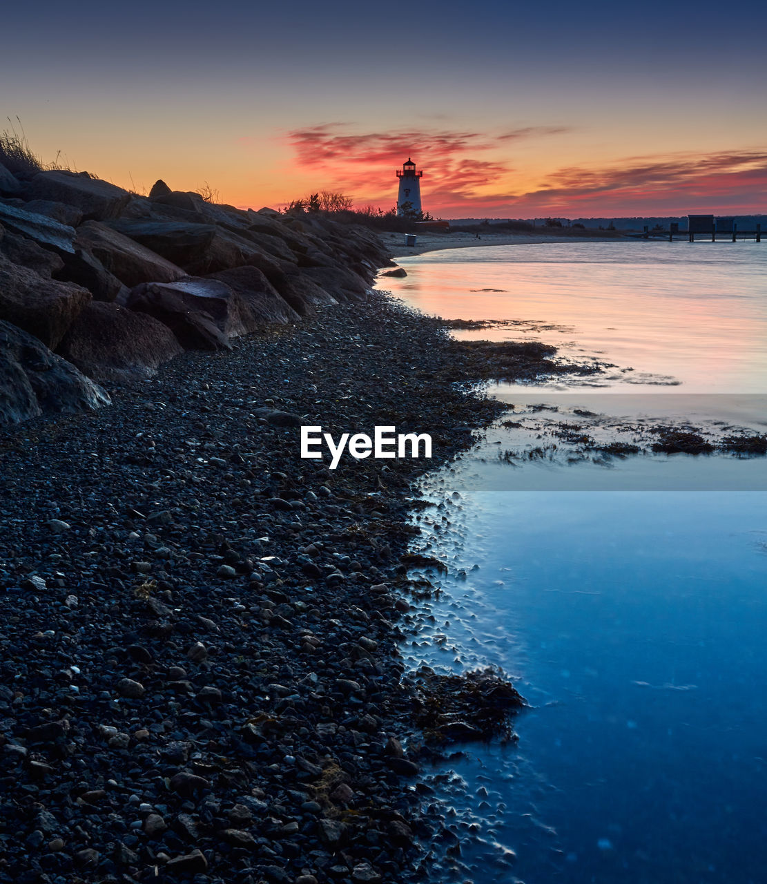 LIGHTHOUSE BY SEA AGAINST SKY DURING SUNSET