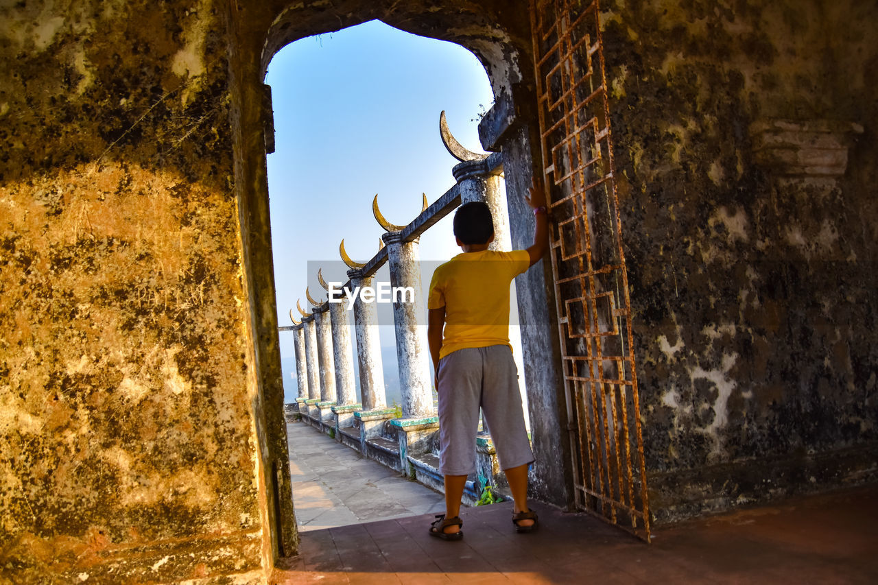 Rear view of boy standing by wall
