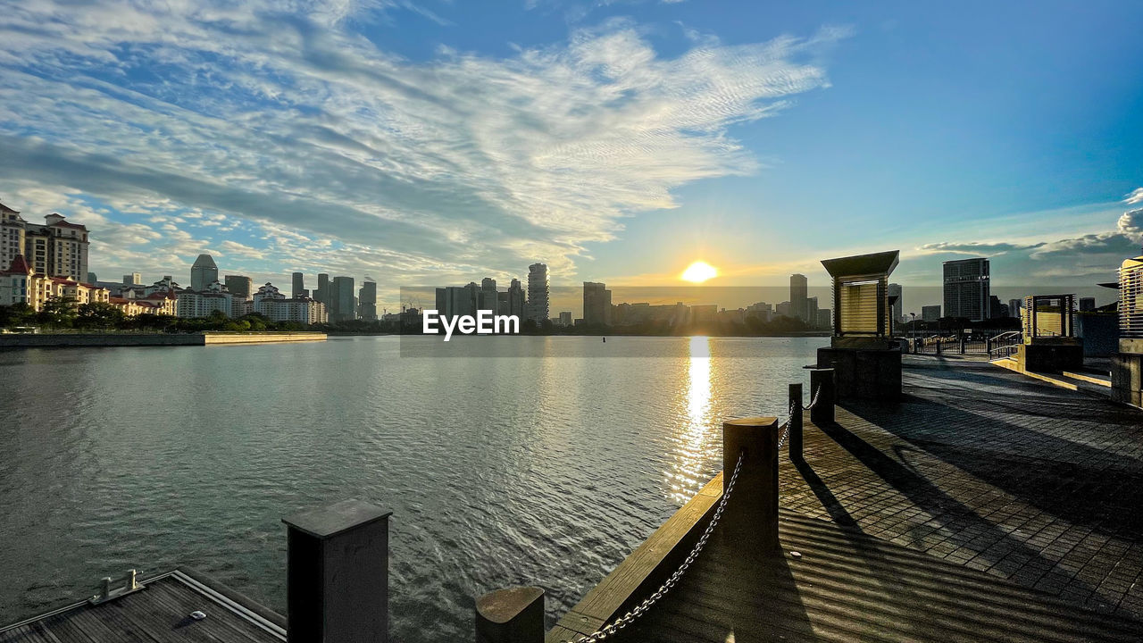 CITY BY RIVER AGAINST SKY DURING SUNSET