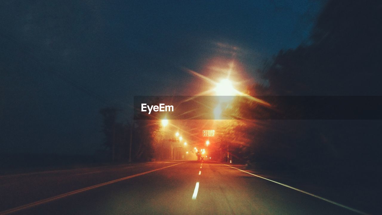 ROAD AMIDST ILLUMINATED SKY AT NIGHT