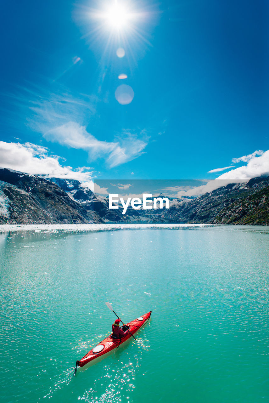 Woman kayaking in glacier bay national park with glacier in background