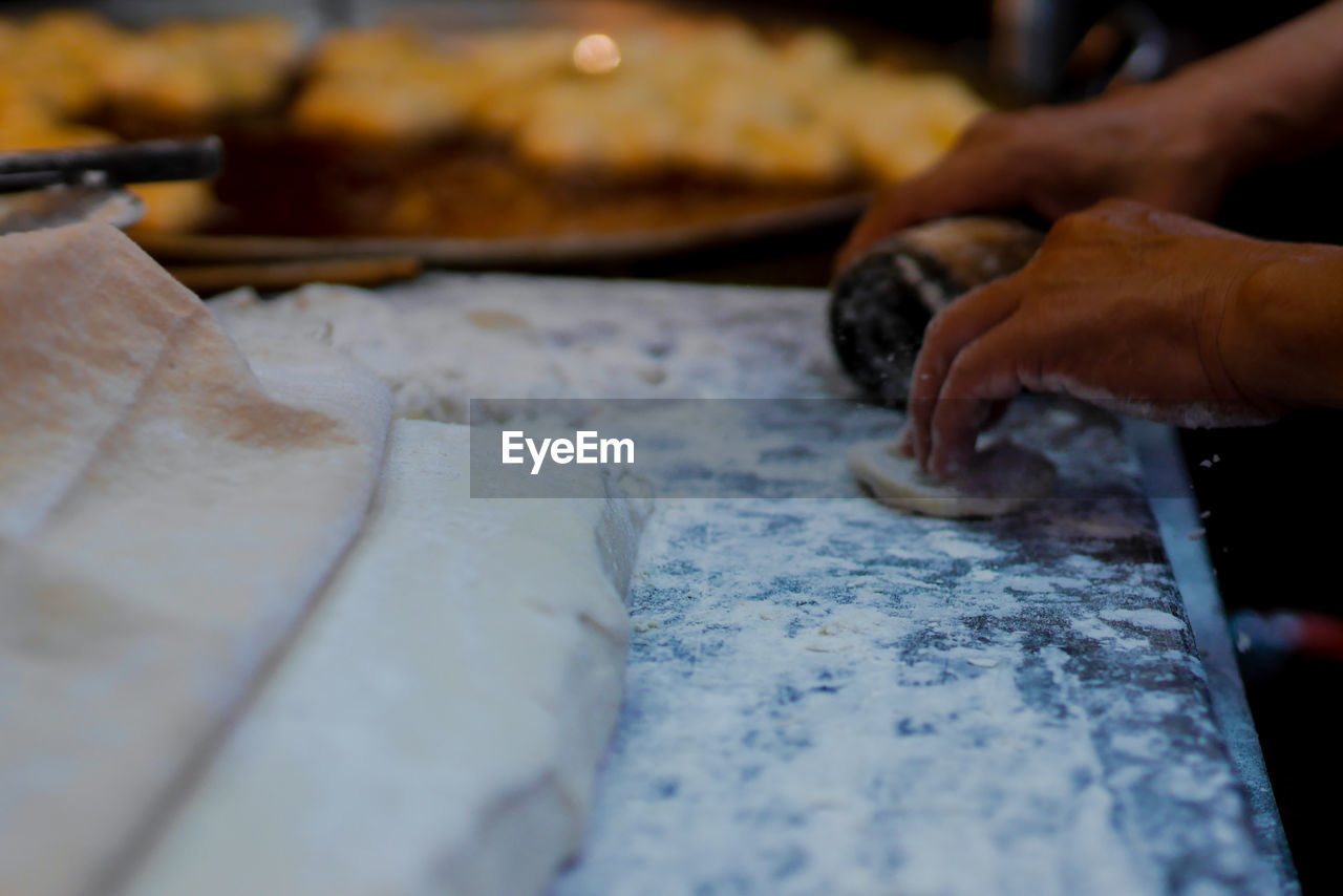 CLOSE-UP OF PERSON PREPARING FOOD IN KITCHEN