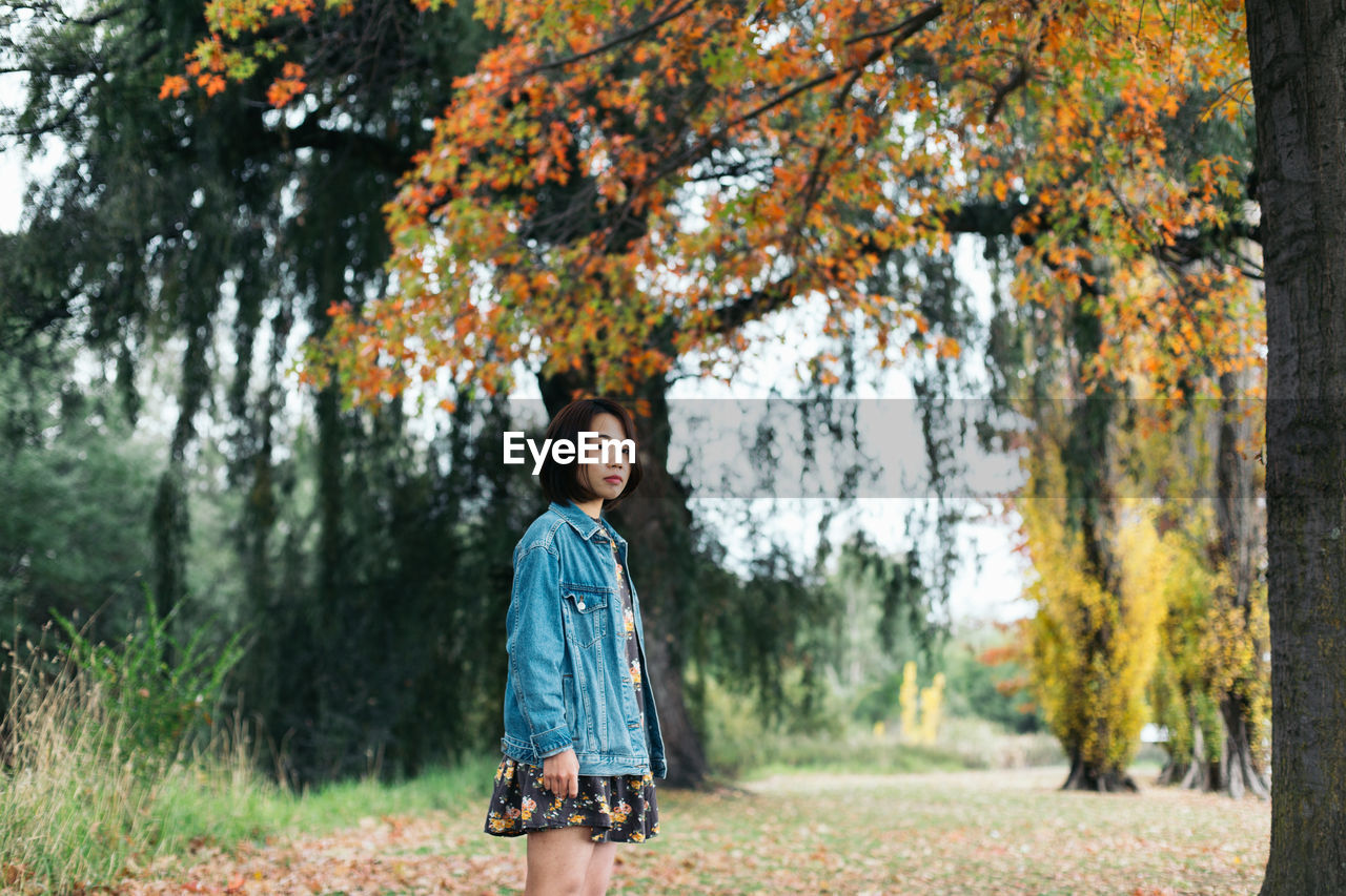 Portrait of woman standing against trees in park