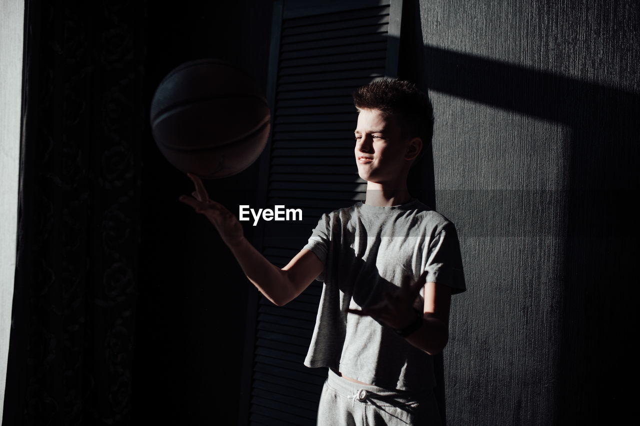 Young man looking at camera while standing against wall