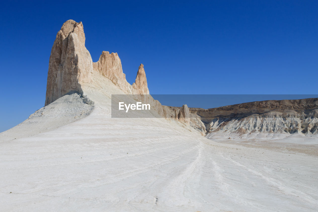 panoramic view of rock formations in desert against clear blue sky