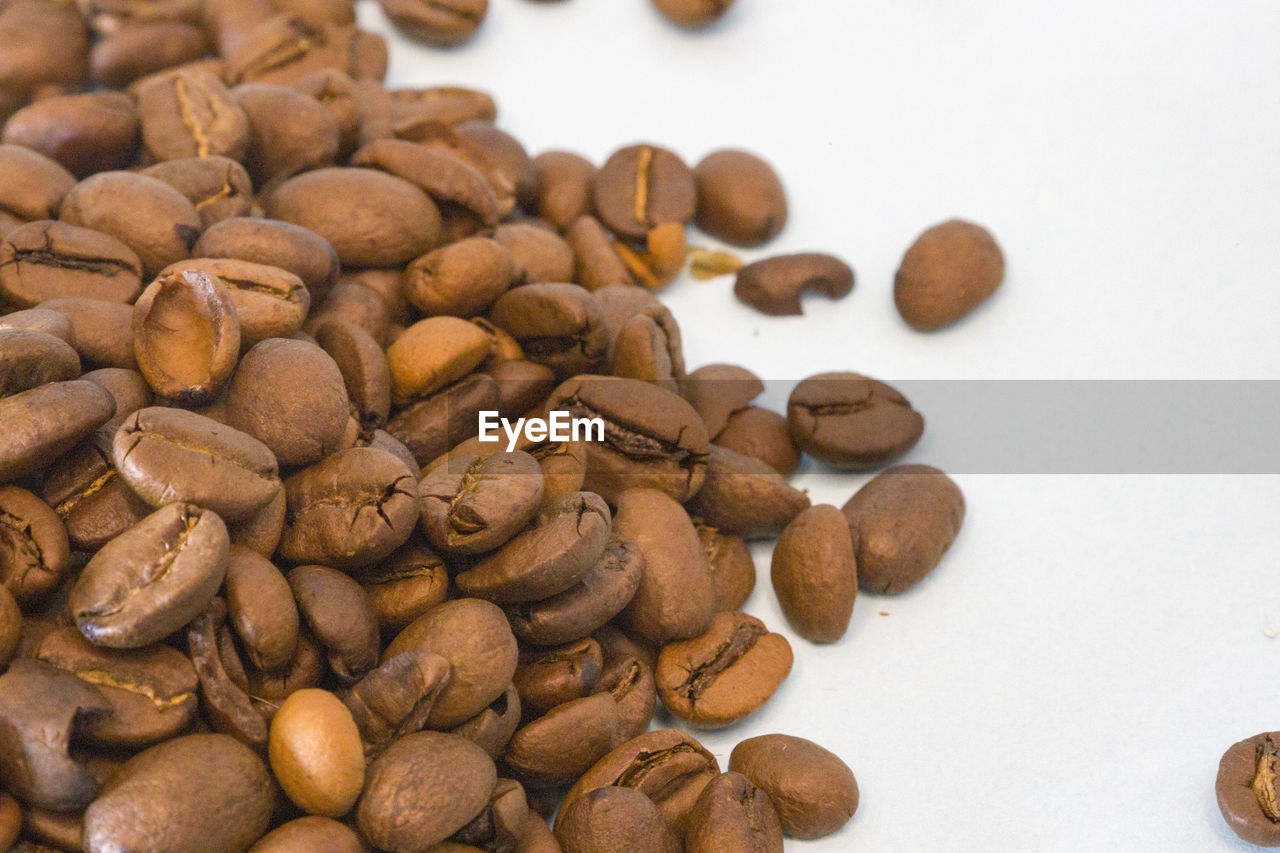 high angle view of roasted coffee beans against white background