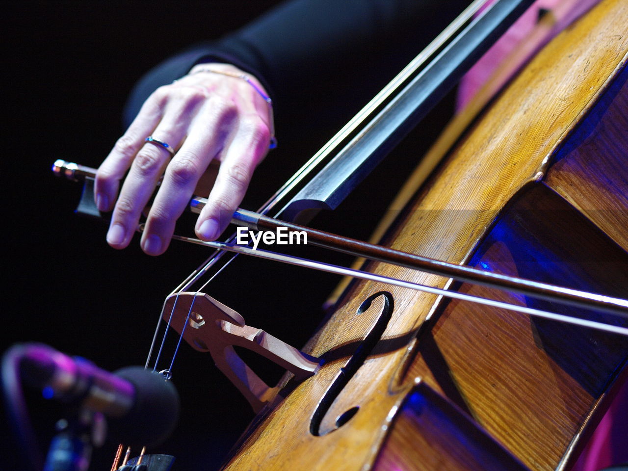 Hand playing cello strings at classical concert