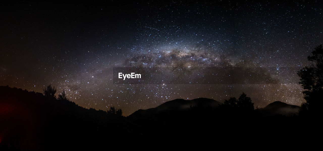 Low angle view of silhouette mountain against sky at night