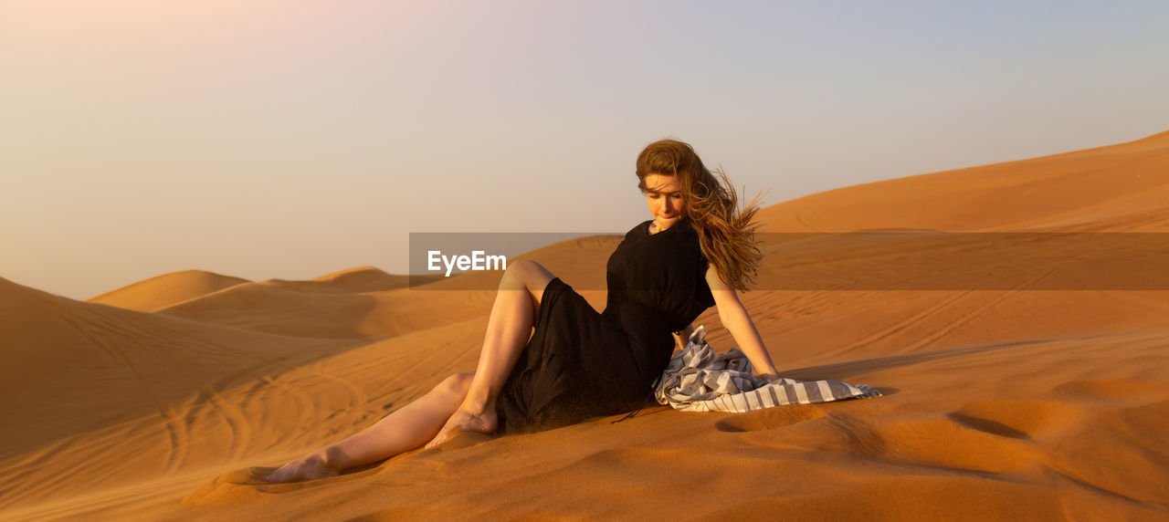 Young woman in desert against sky