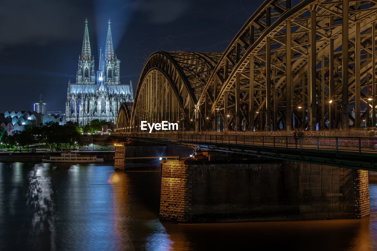 Bridge over river at night on cologne with cathedral in the background 