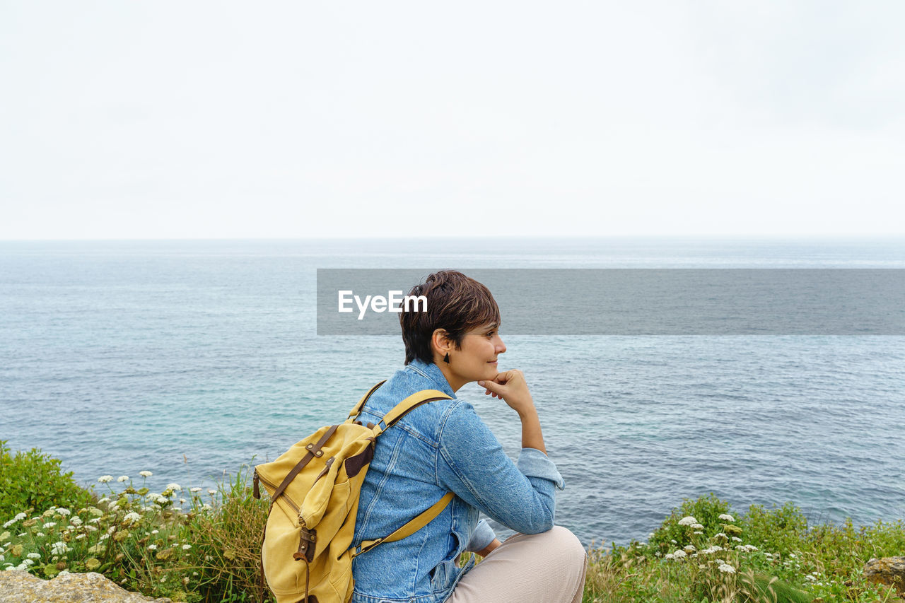 rear view of woman standing against sea against clear sky