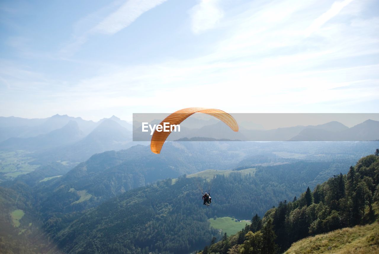 PERSON PARAGLIDING OVER MOUNTAIN AGAINST SKY