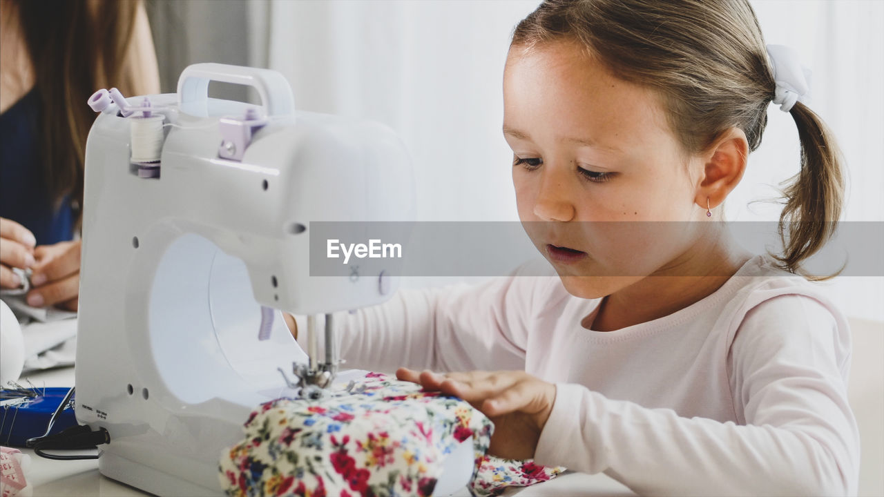 Close-up of cute girl sewing textile at home
