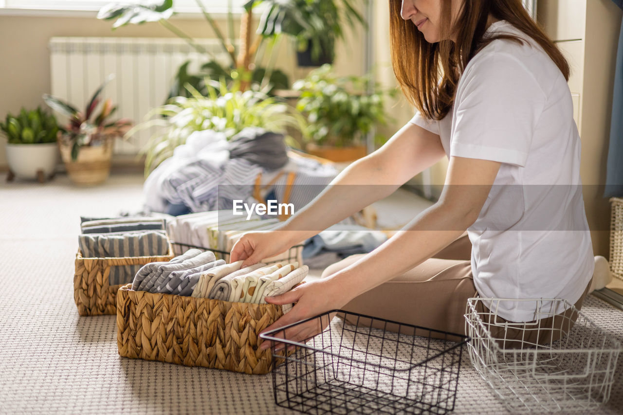 midsection of woman with vegetables in basket at home